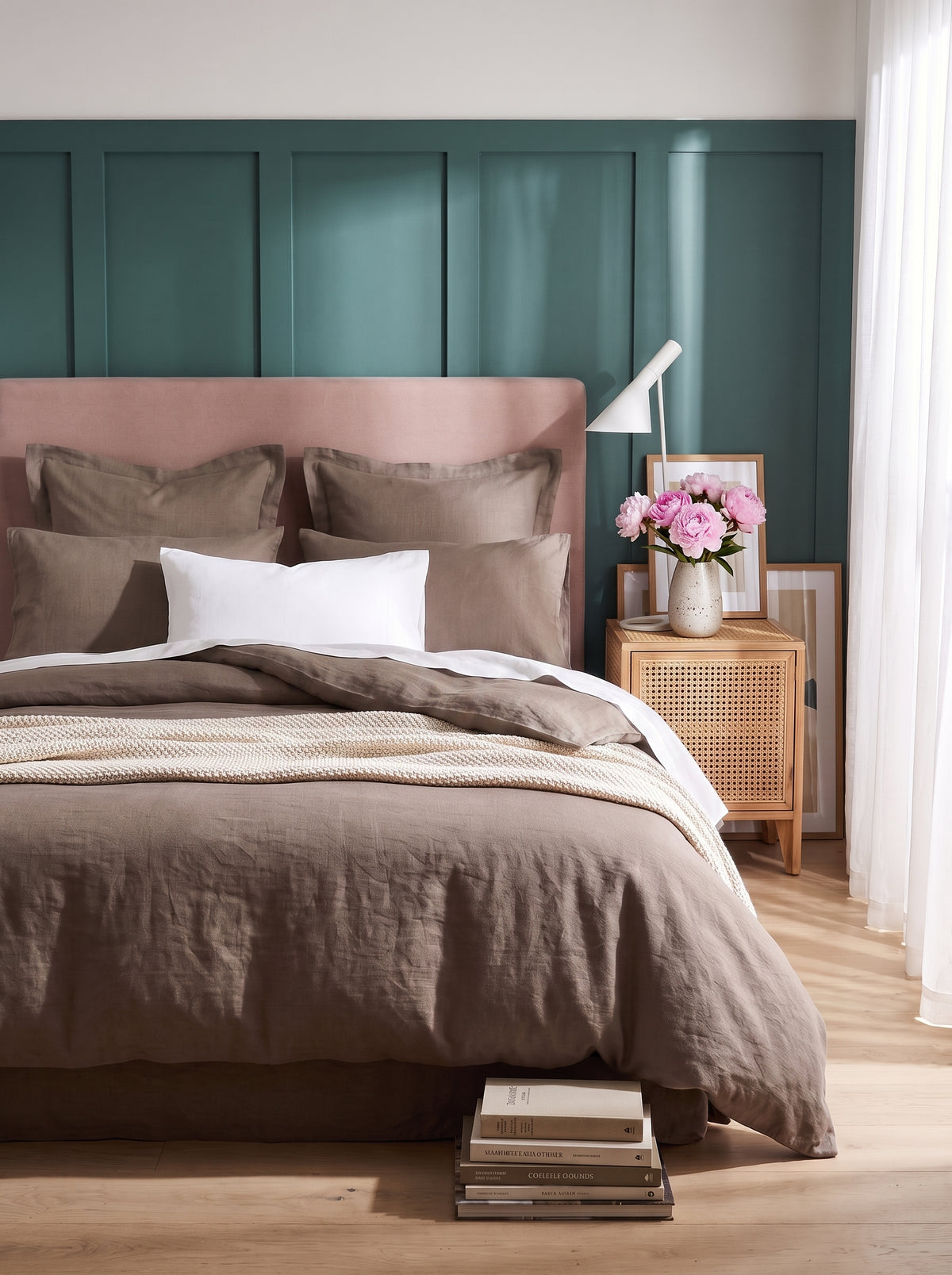 Warm taupe washed linen bedding on a bed with a blush headboard against teal panelling