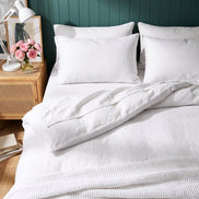 Warm white washed linen bedding, close view against deep green panelling