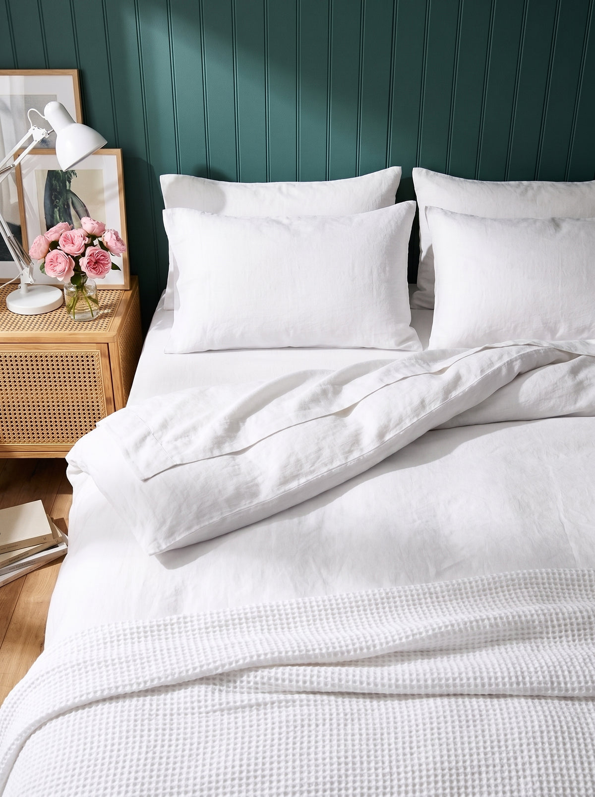 Warm white washed linen bedding, close view against deep green panelling