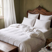 Warm white washed linen bedding on an antique carved wooden bed