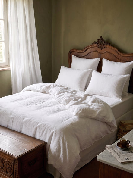 Warm white washed linen bedding on an antique carved wooden bed
