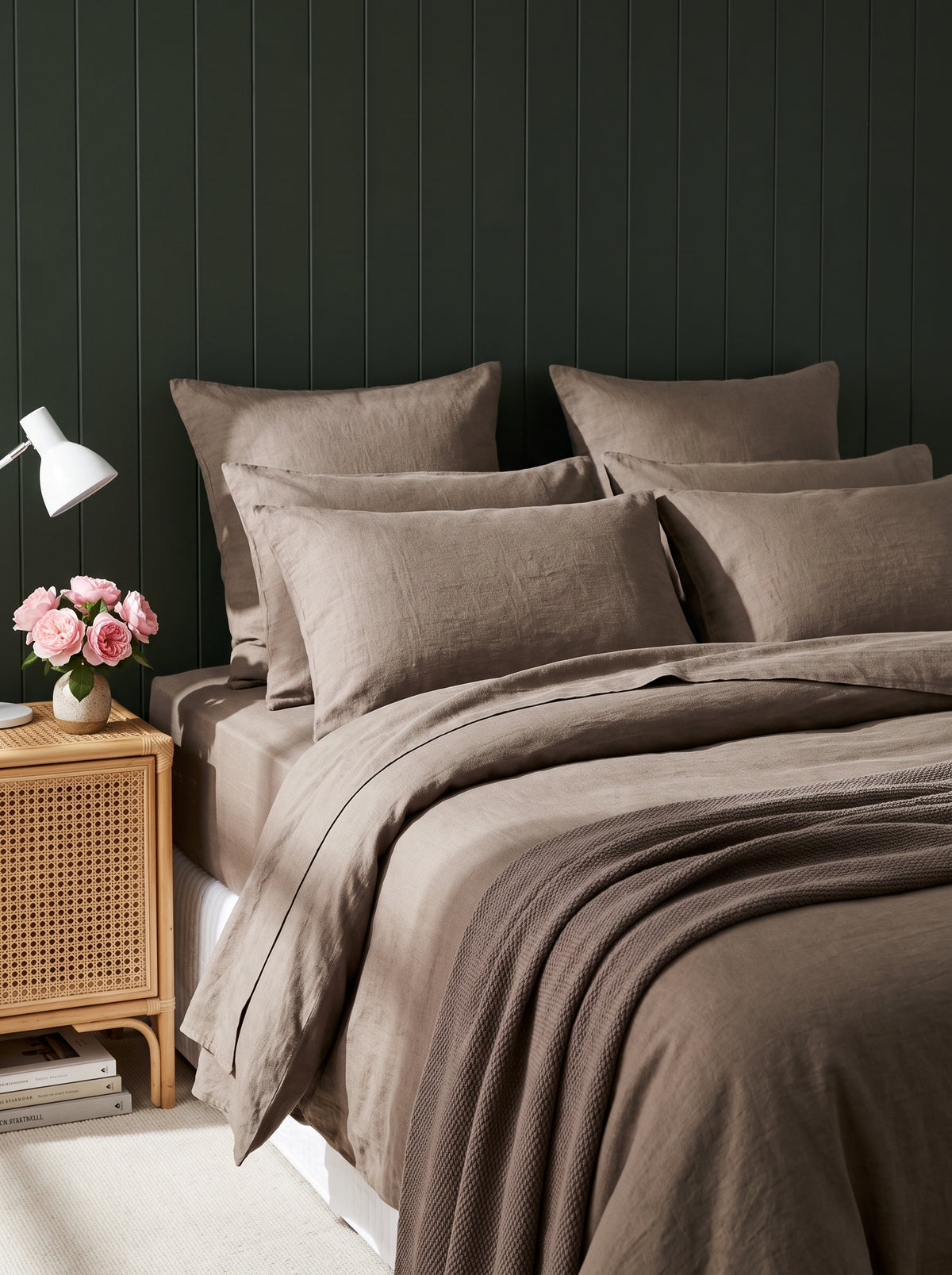 Warm taupe washed linen bedding against deep green panelling, evening