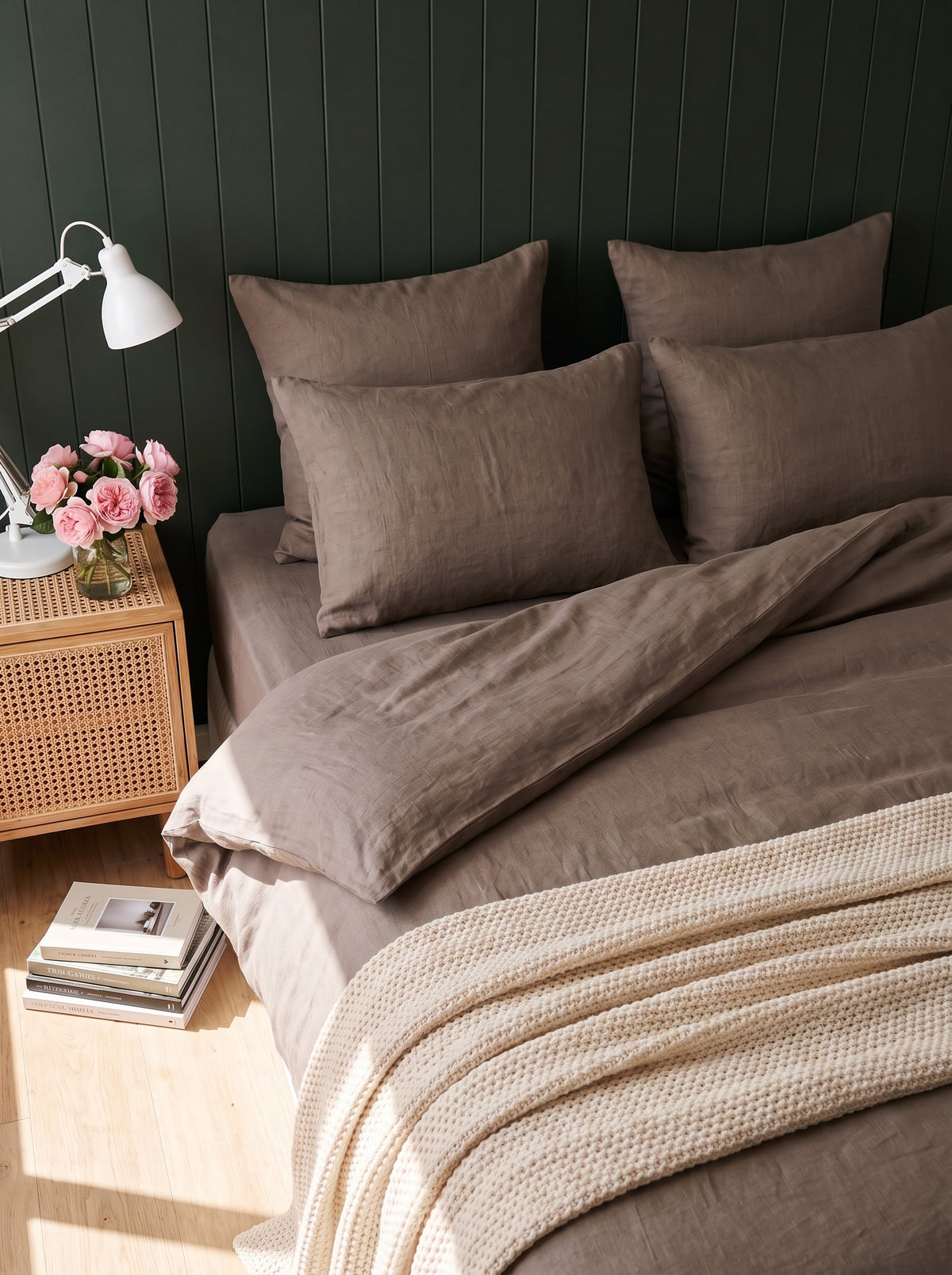 Warm taupe washed linen bedding against deep green panelling, daylight