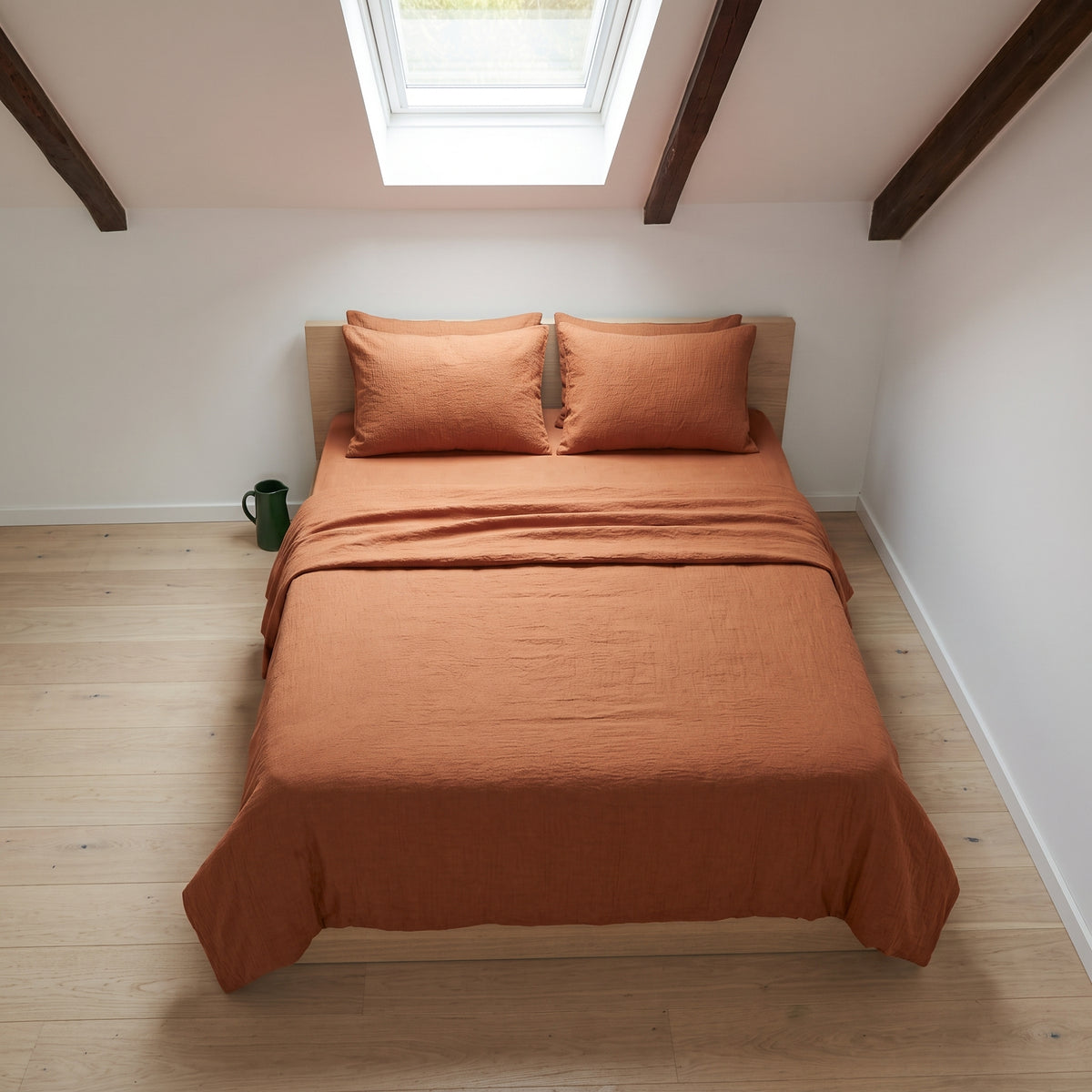 Close view of the corner of the rust duvet cover folded back over a pillow