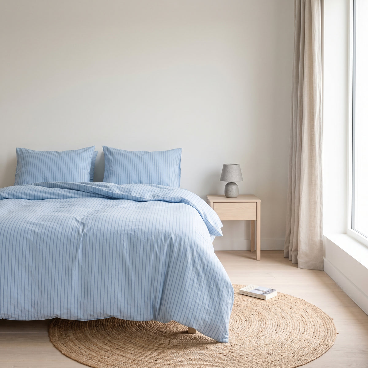 Pale blue striped duvet cover on a low wooden bed in an attic room
