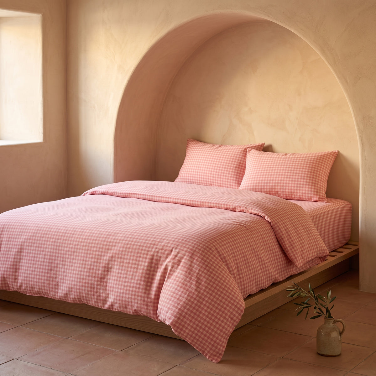 Dusty pink checked duvet cover on a bed set into an arched alcove