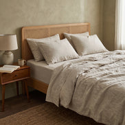 Oatmeal duvet cover on a low wooden bed beside a curtained window