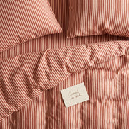 Dusty terracotta striped bed linen set seen from above
