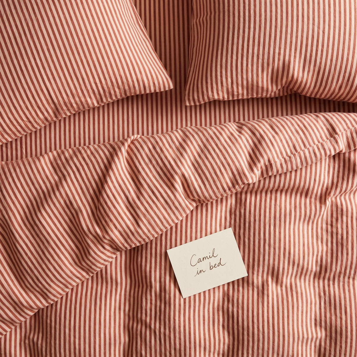 Dusty terracotta striped bed linen set seen from above
