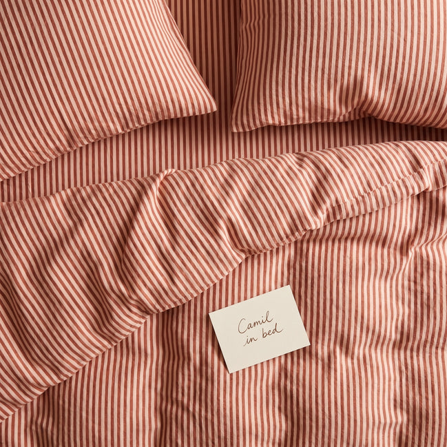 Dusty terracotta striped bed linen set seen from above