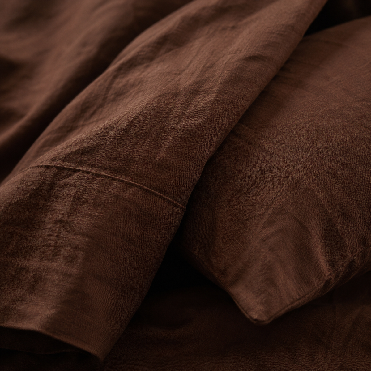 Close view of the corner of the deep brown duvet cover folded back over a pillow