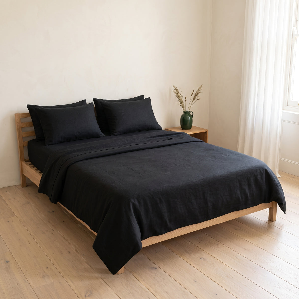 Black duvet cover on a low wooden bed in a warm, softly lit room