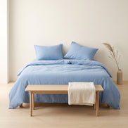 Side view of a bed made up in pale blue striped bedding