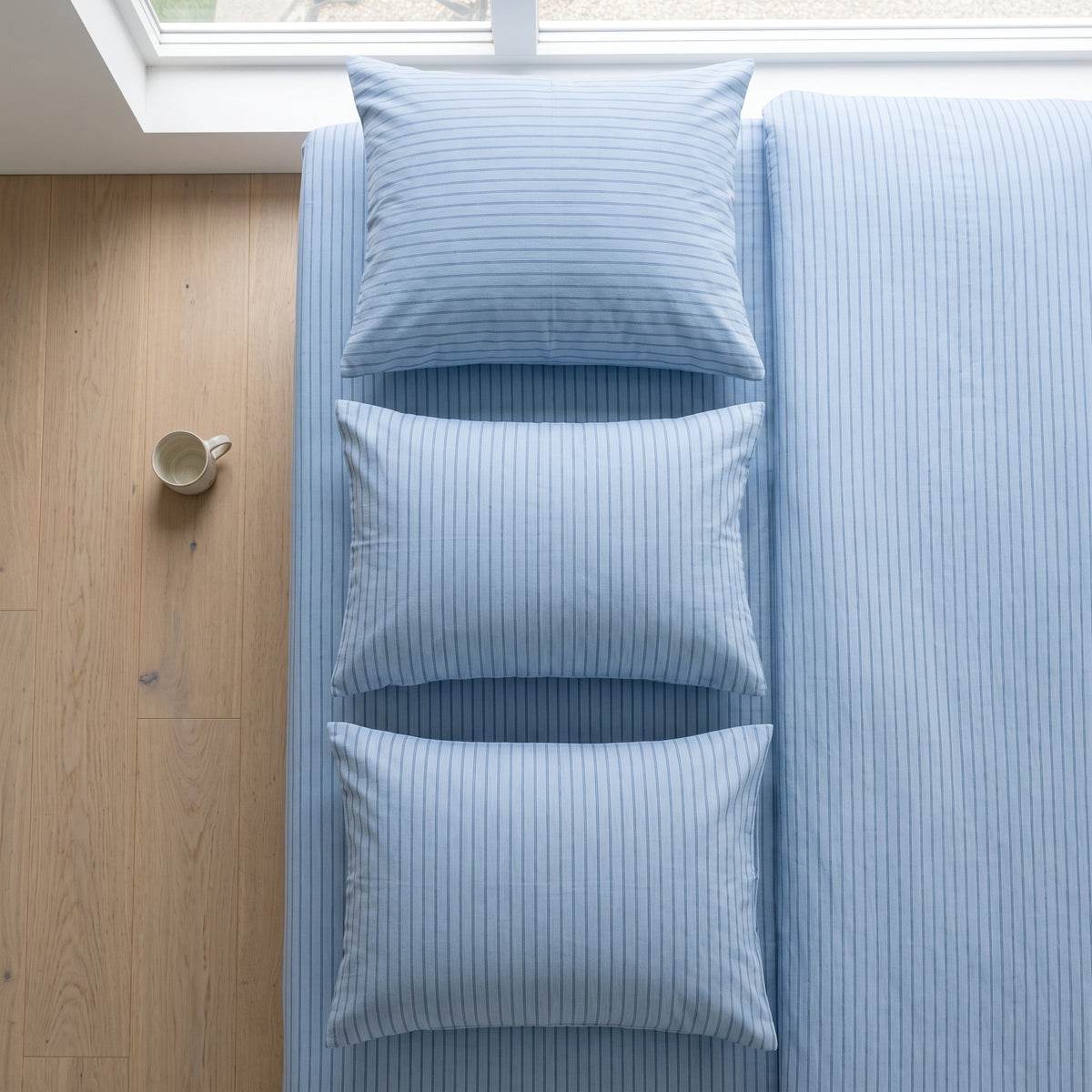 Pale blue striped bedding seen from above across the whole bed