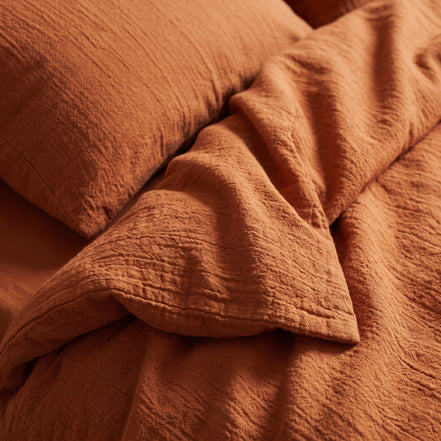 Rust duvet cover on a low wooden bed in an attic room with a sloping ceiling