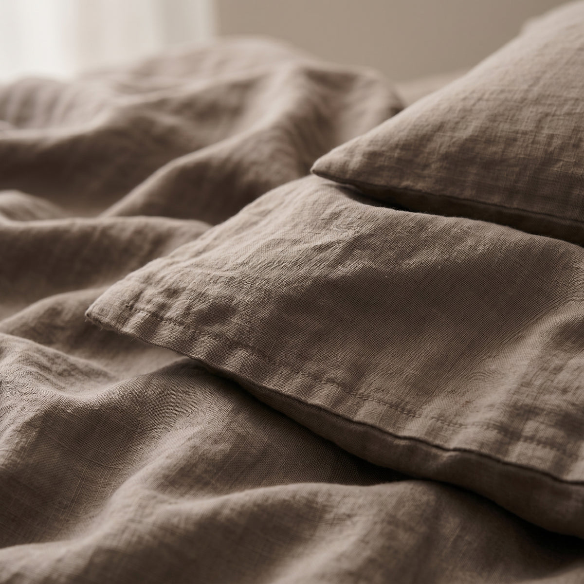 Close view of the corner of the taupe linen folded back over a pillow