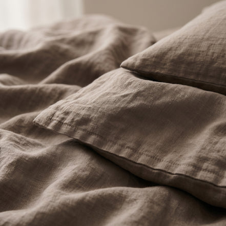 Close view of the corner of the taupe linen folded back over a pillow