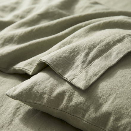 Close view of the sage green linen folded back over a pillow