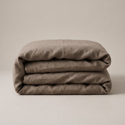 Taupe duvet cover folded into a neat block and photographed against a plain background