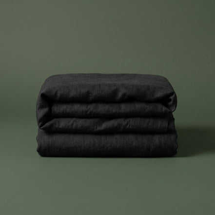 Black duvet cover folded into a neat block and photographed against a plain background