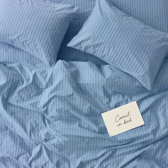 Pale blue striped bed linen set seen from above