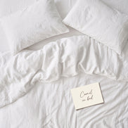 Warm white bed linen set laid out, duvet cover and pillowcases seen from above