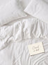 Warm white bed linen set laid out, duvet cover and pillowcases seen from above