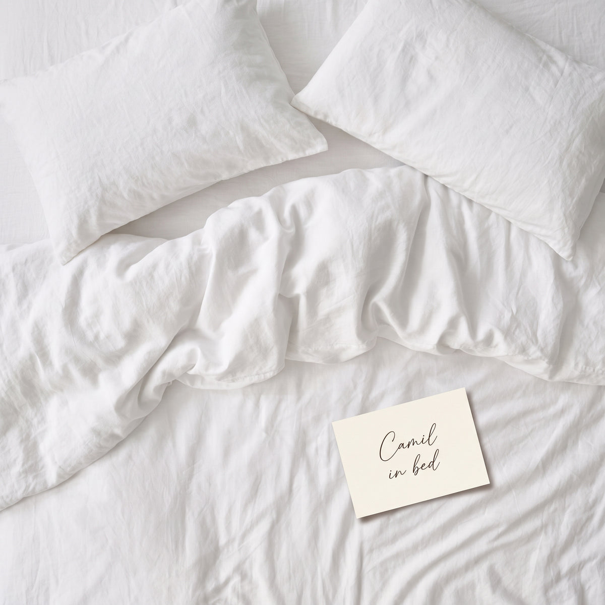 Warm white bed linen set laid out, duvet cover and pillowcases seen from above