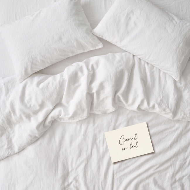 Warm white bed linen set laid out, duvet cover and pillowcases seen from above