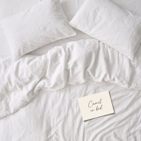 Warm white bed linen set laid out, duvet cover and pillowcases seen from above
