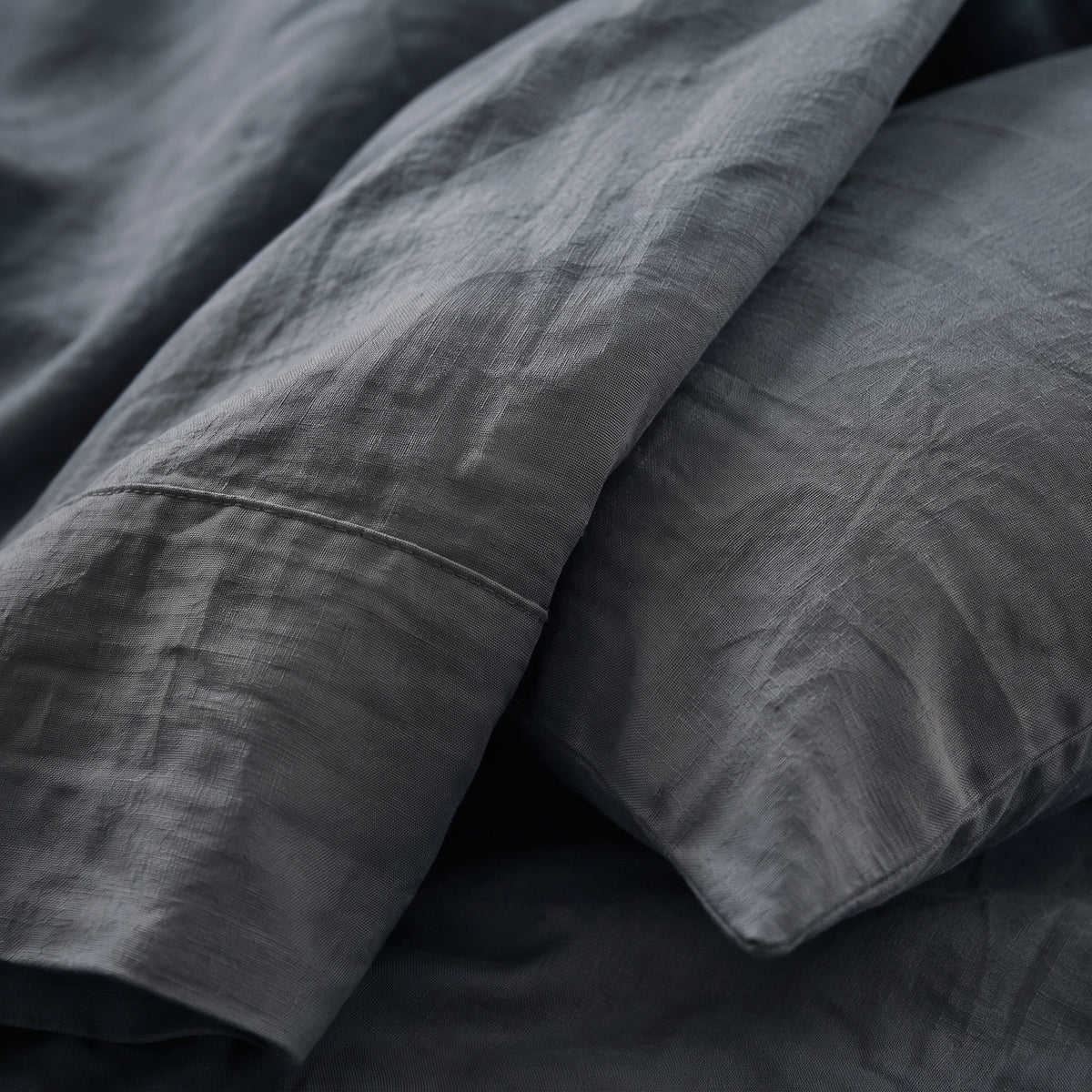 Close view of the corner of the slate grey duvet cover folded back over a pillow